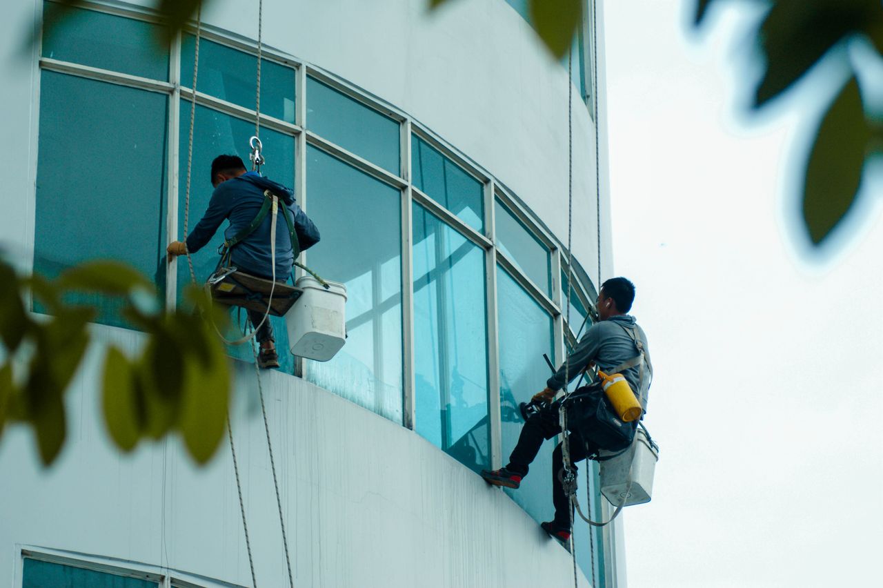 about-01 Window cleaners suspended on ropes clean a high-rise buildings glass exterior.